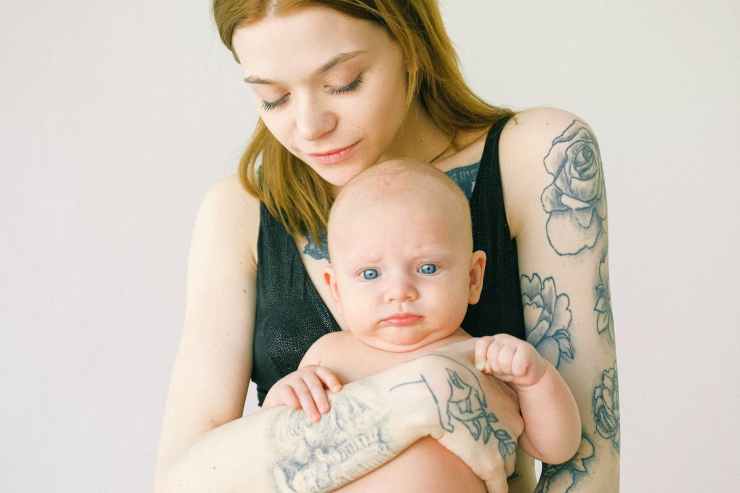 woman with tattoo carrying baby